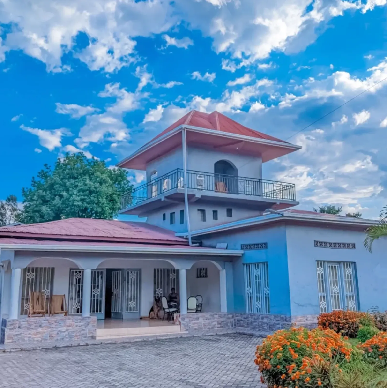 A blue and white house with an arched porch and a tower room above the roof